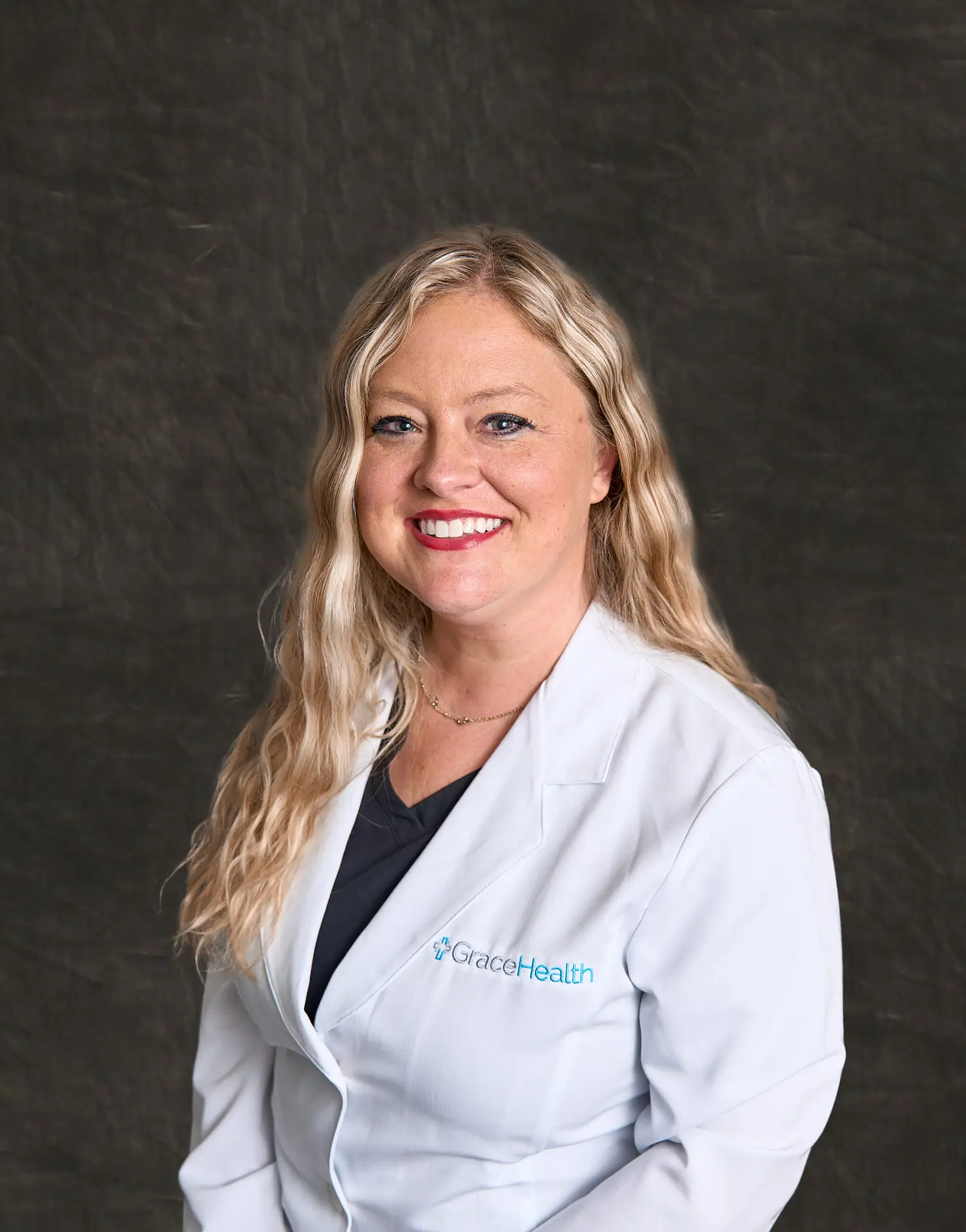 A professional headshot of April Hurley, a blonde woman with a warm smile, wearing a white medical coat.