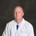 Jerry Kunkel, PMHNP, a behavioral health provider at Grace Health, smiles while wearing a white lab coat.