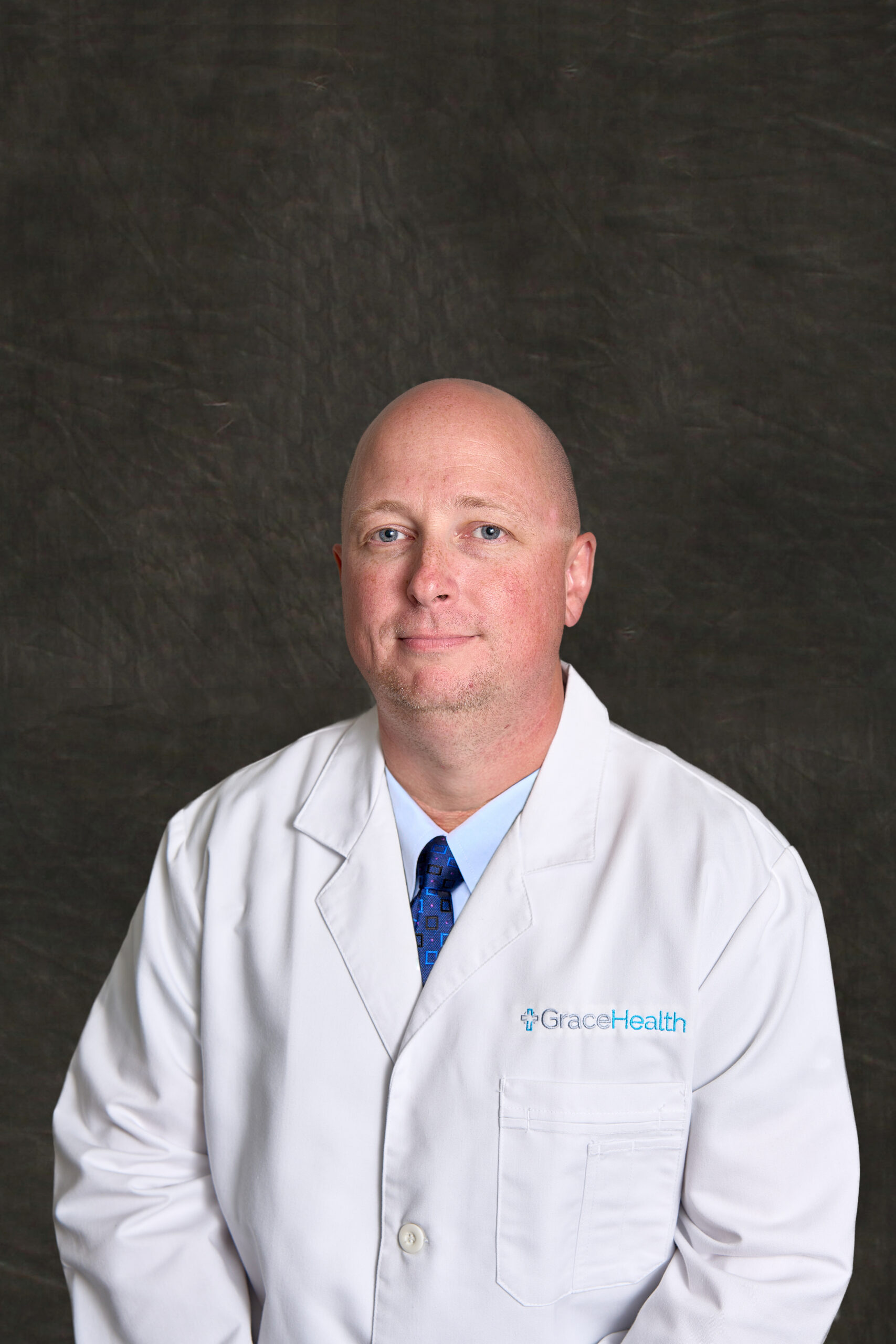 Jerry Kunkel, PMHNP, a behavioral health provider at Grace Health, smiles while wearing a white lab coat.