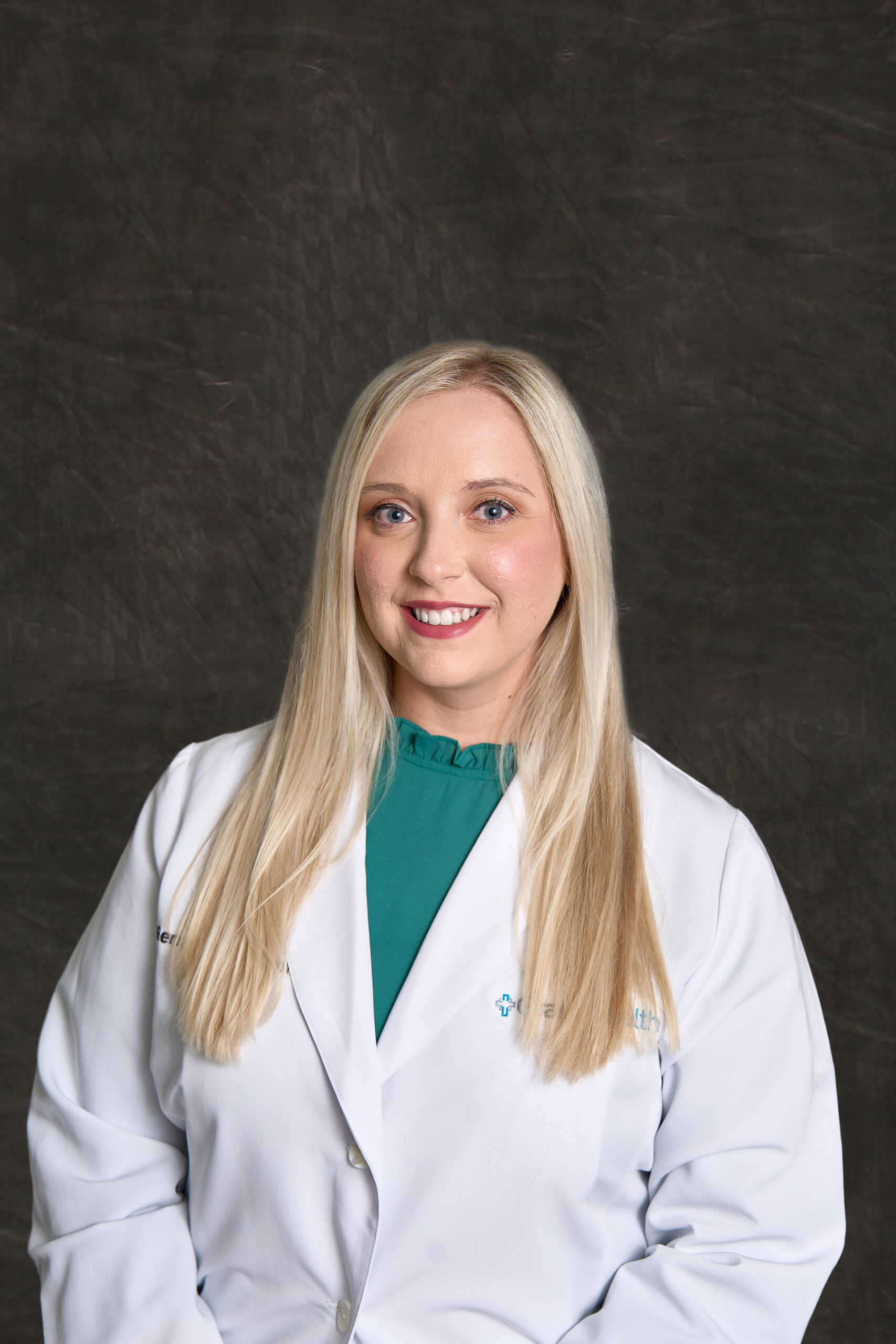 A professional headshot of Renzee Jarvis, a young blonde woman smiling, wearing a white pharmacist's coat over a teal blouse.